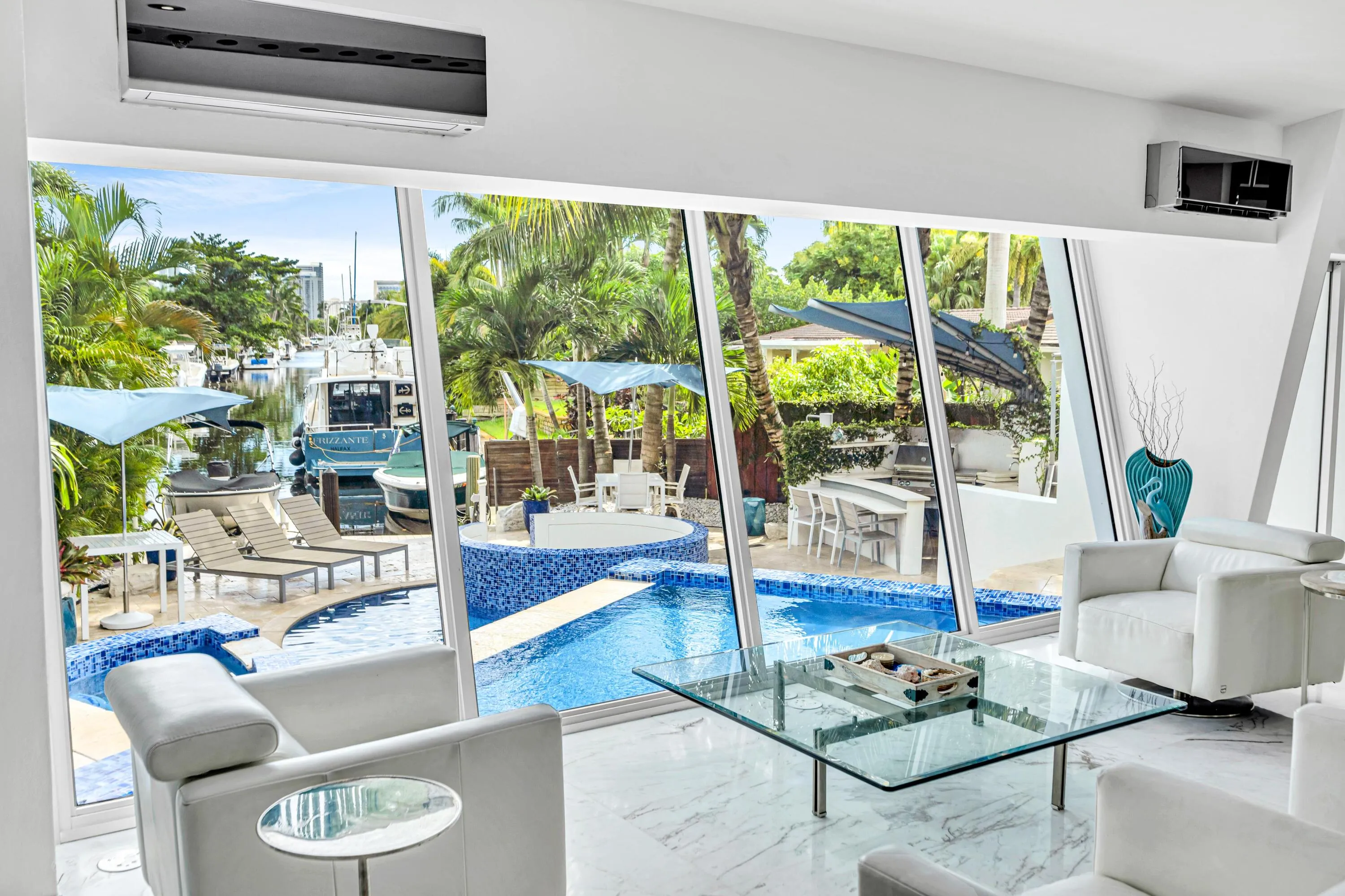 Expansive windows overlooking a pool with blue mosaic tile and a waterway