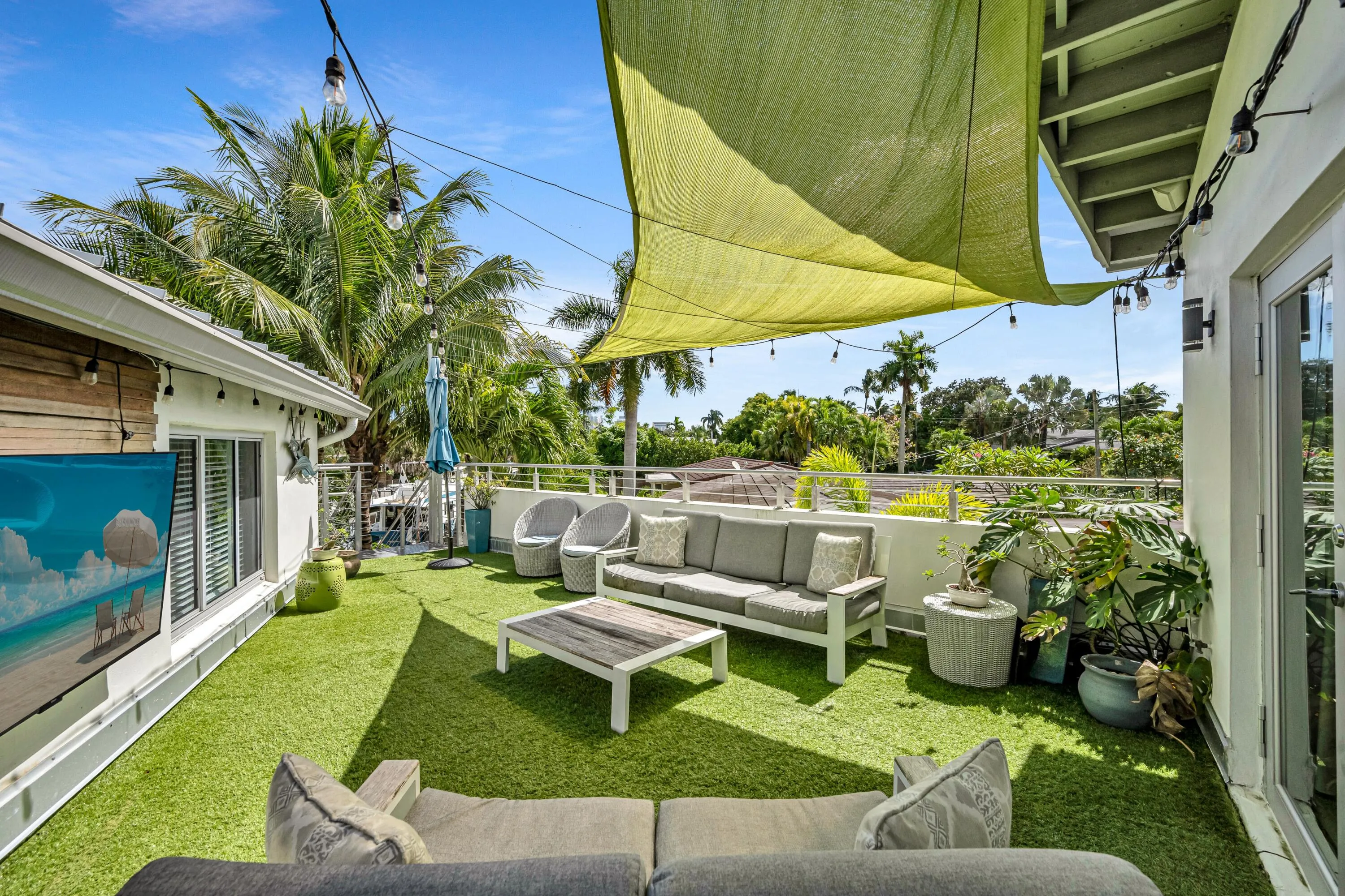Rooftop deck featuring artificial turf, a light-colored sunshade, string lighting, and exterior French doors