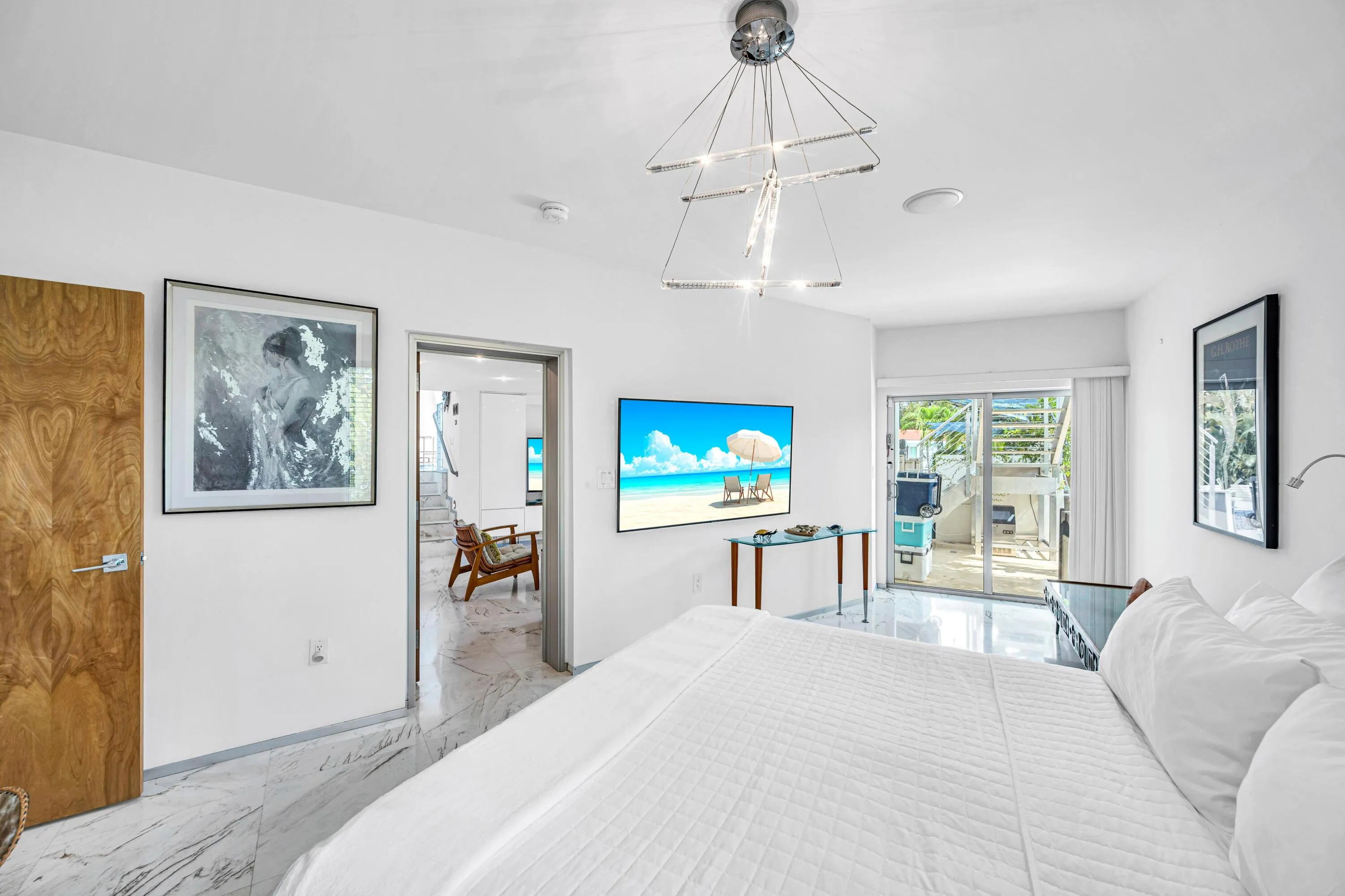White walls, marble-finish flooring, wood-finish door, and a modern chandelier