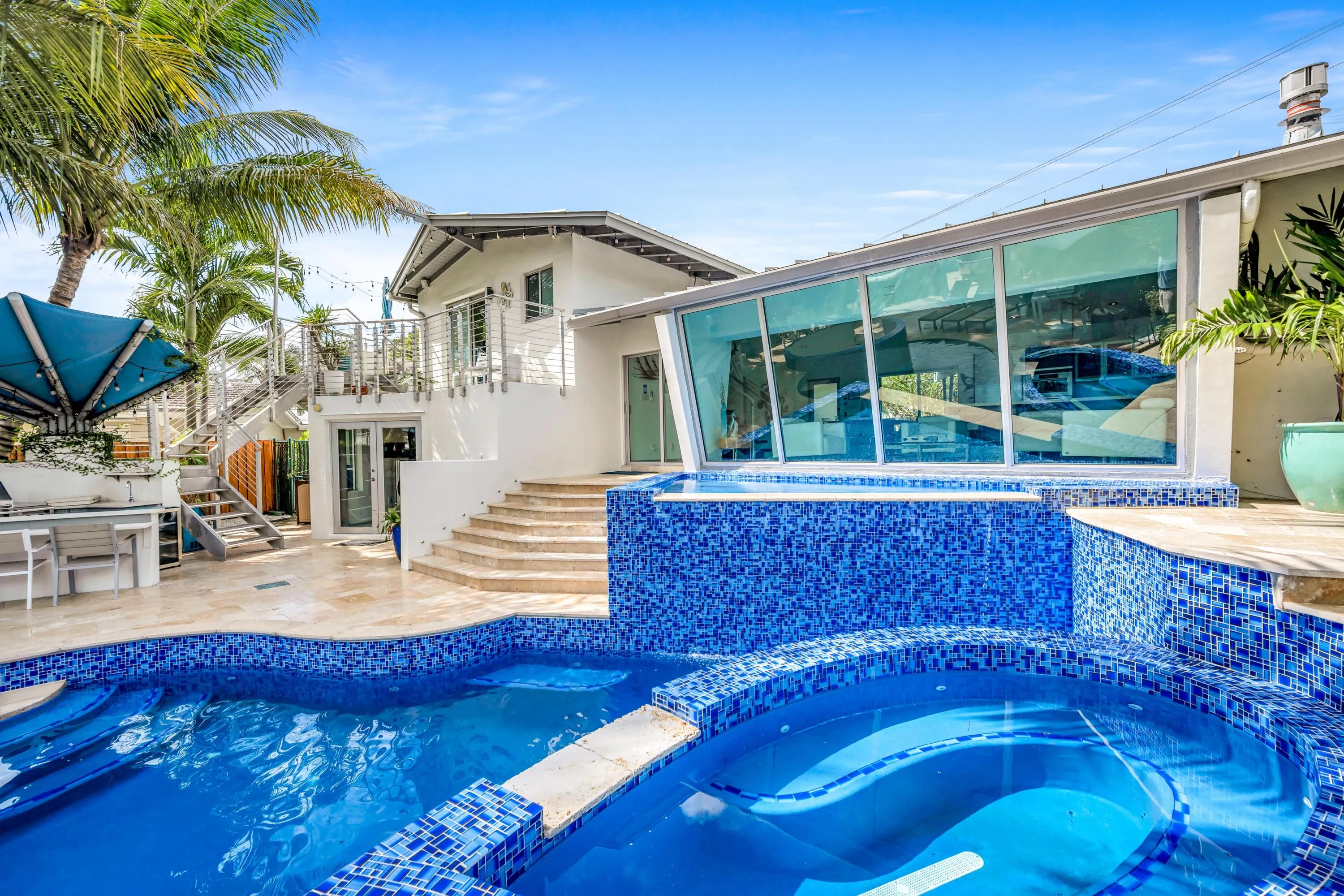 Resort-style backyard oasis featuring a sparkling blue mosaic-tiled saltwater pool and spa with integrated lounging ledge