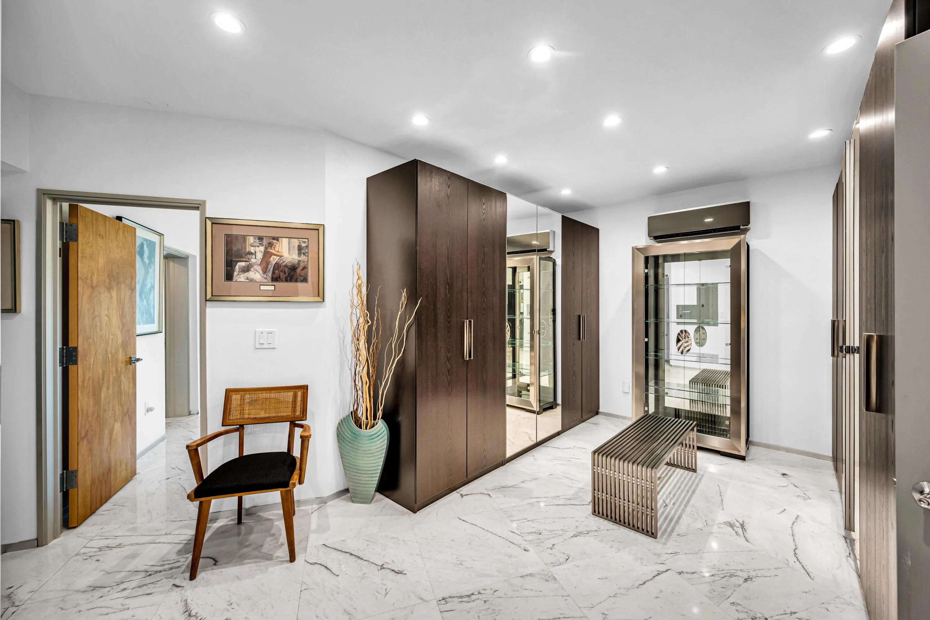 Recessed lighting, white walls, wood-finish flooring, built-in dark wood cabinetry, and a display cabinet with glass doors