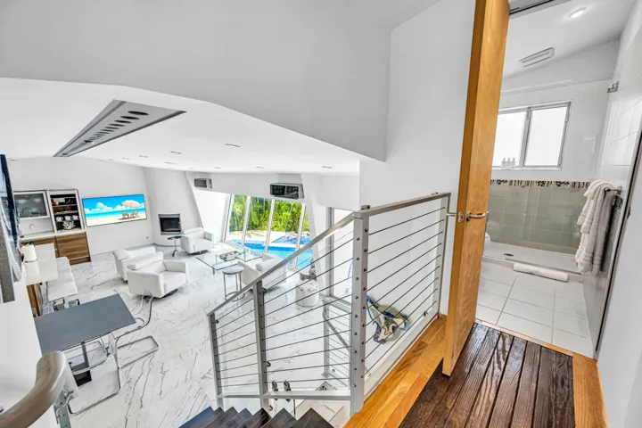 White marble-look flooring, glass and cable railing, built-in fireplace, full-height windows, and a built-in shower with tiled walls