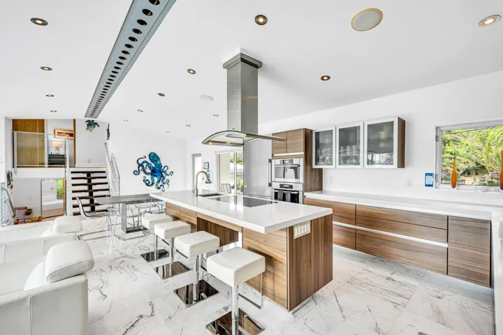 Open-concept kitchen featuring an expansive island, wood-finish cabinetry, integrated stainless steel appliances, and recessed lighting