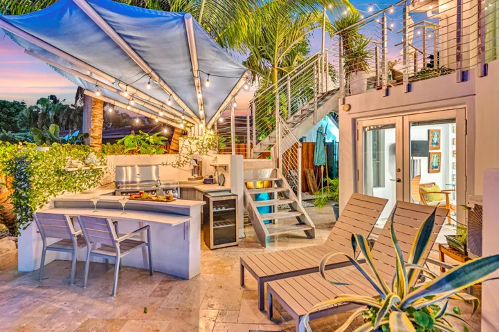 Outdoor kitchen with stainless steel grill, under-counter beverage cooler, and built-in bar seating