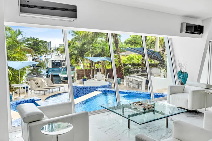 Expansive windows overlooking a pool with blue mosaic tile and a waterway