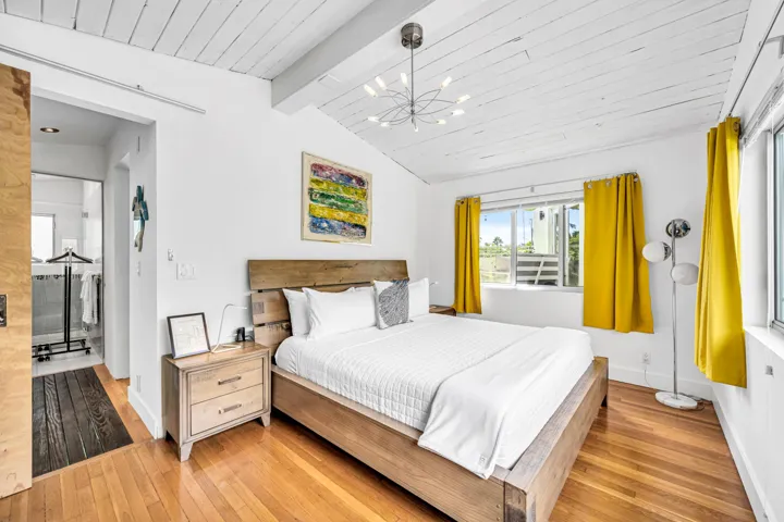Vaulted wood-plank ceiling, wood-finish flooring, large window, and modern chandelier