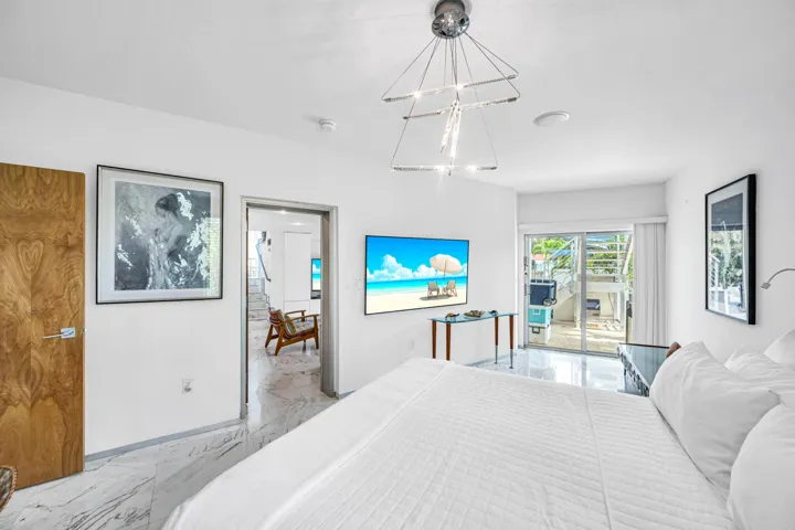 White walls, marble-finish flooring, wood-finish door, and a modern chandelier