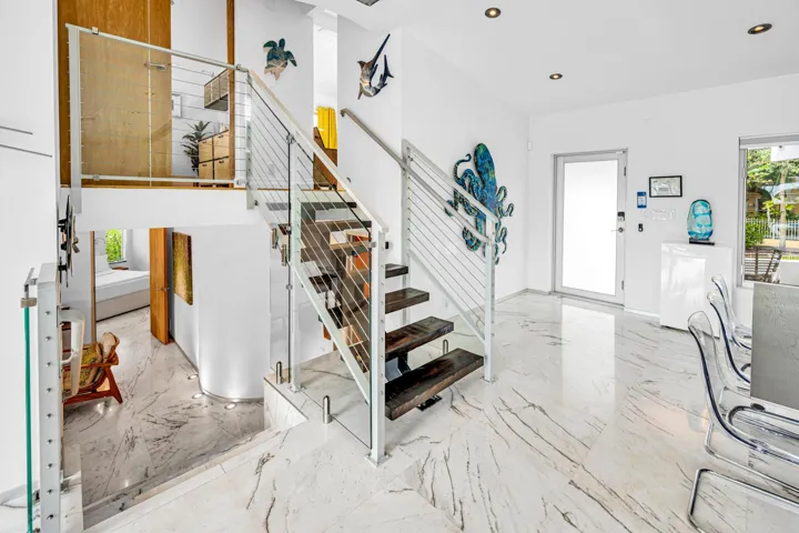 Modern staircase featuring wood treads, glass panels, and stainless steel railings