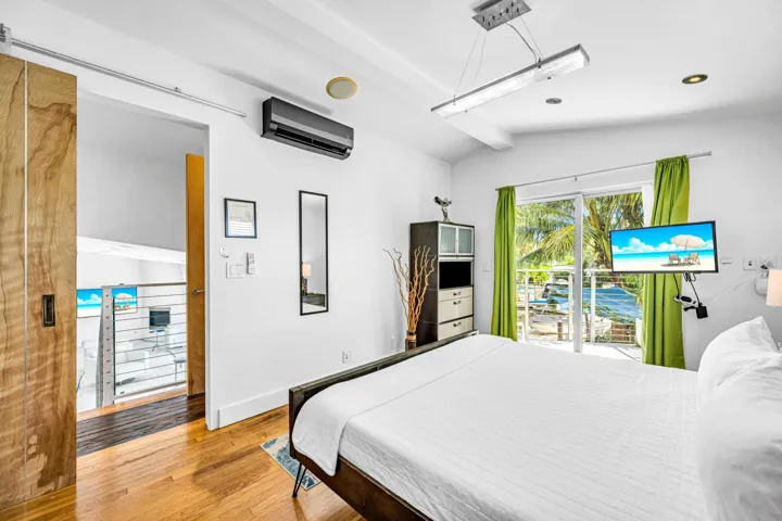 Hardwood flooring, sliding barn door, wall-mounted air conditioning unit, recessed lighting, and glass sliding doors with exterior access
