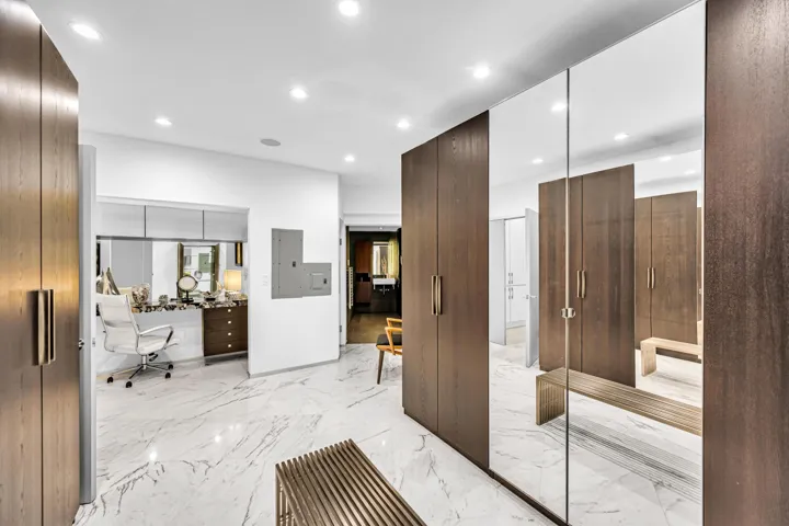 White marble-look tile flooring, recessed lighting, wood-finish cabinetry, full-height mirrored wardrobe doors, and modern wall-mounted light fixtures