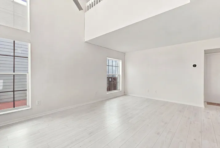 Soaring 15-foot ceilings and expansive windows fill the living room with natural light, creating a warm and welcoming space for everyday living and entertaining. The thoughtfully designed floor plan flows effortlessly from the living area to a convenient powder room and the private backyard, making the home feel open, connected, and inviting.