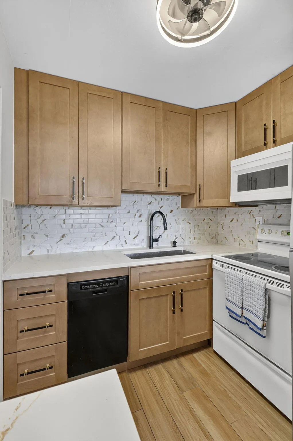 Modern kitchen featuring wood-finish cabinetry, white countertops, a tiled backsplash, and wood-finish flooring