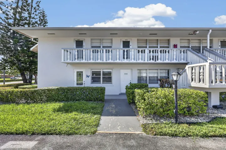 Two-story building with white exterior, second-story balcony with baluster railing, and exterior staircase