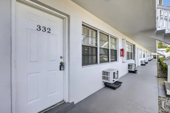 Unit 332 features a covered breezeway entry with a six-panel white composite door, digital keypad lock, and continuous window line along the facade