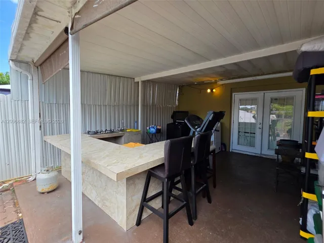 Spacious covered patio featuring a built-in bar, cooktop, sink, generous counter space, and bar seating—ideal for outdoor entertaining.