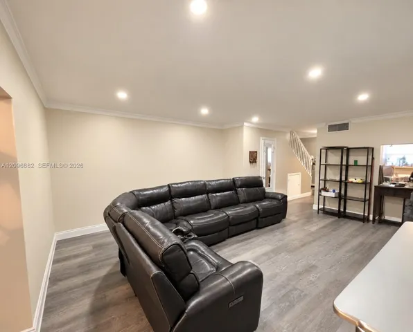 Spacious living area featuring updated flooring, recessed lighting, crown molding, and an open layout ideal for everyday living and entertaining.