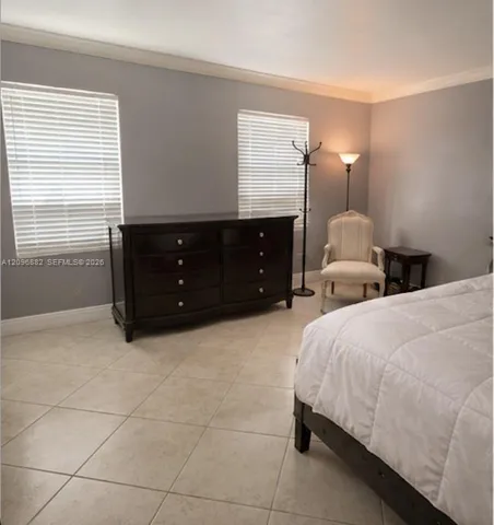 Spacious bedroom featuring tile flooring, crown molding, and multiple windows providing plenty of natural light.