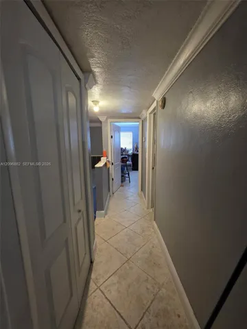 Upstairs hallway featuring tile flooring, crown molding, and access to the bedrooms and bathroom.