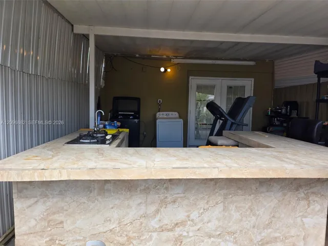 Spacious covered patio featuring a built-in bar, cooktop, sink, generous counter space, and bar seating—ideal for outdoor entertaining.