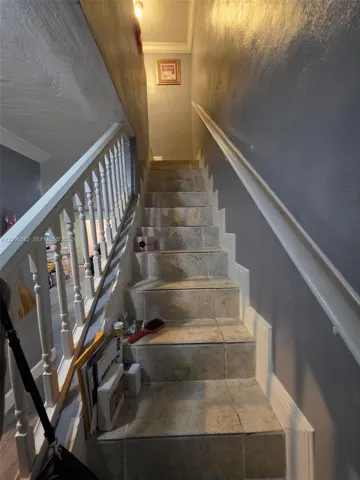 Tiled staircase leading to the upper level, featuring a classic railing and convenient handrail.