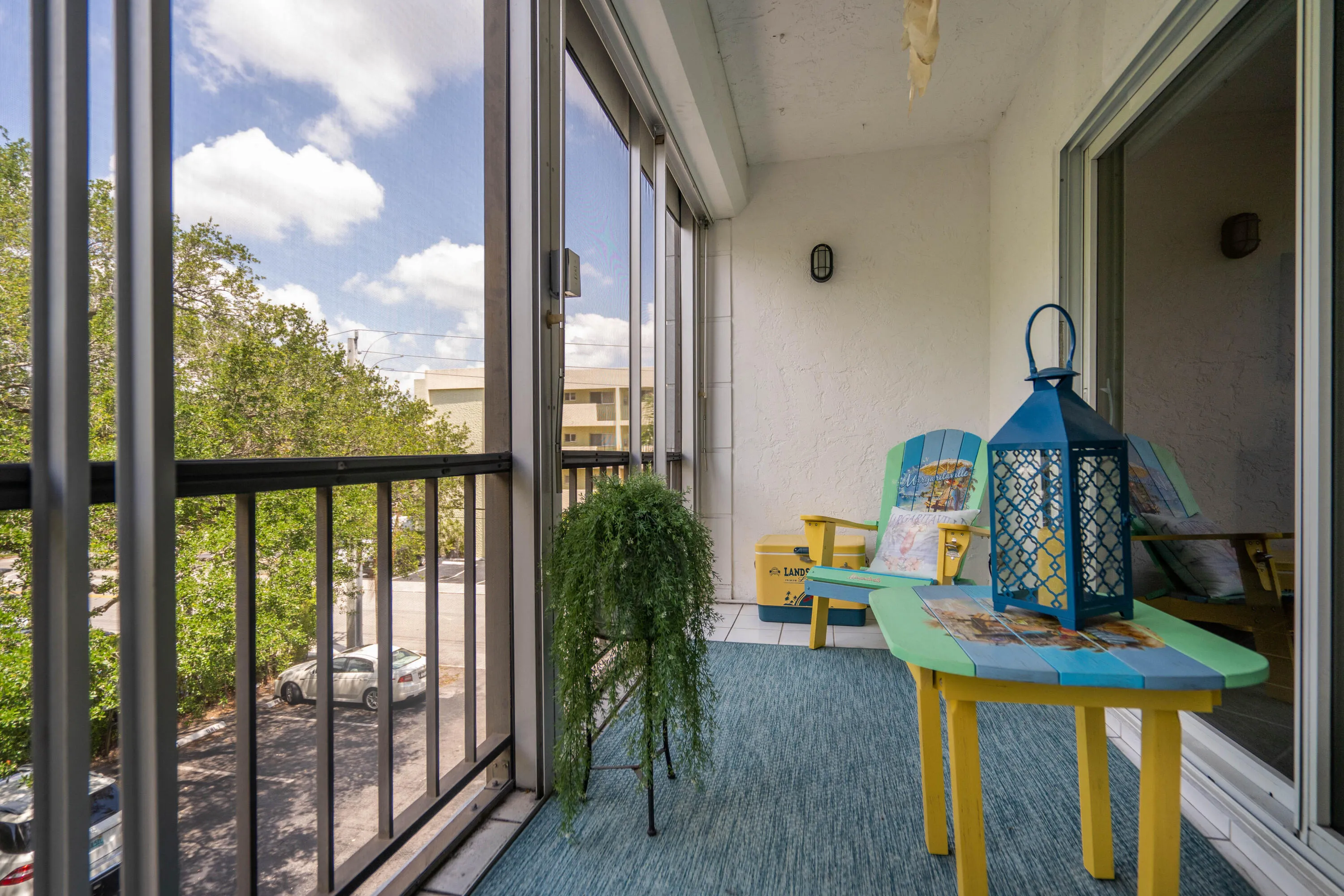 Covered screened porch with blue-gray flooring, black metal railings, and expansive sightlines to mature landscaping