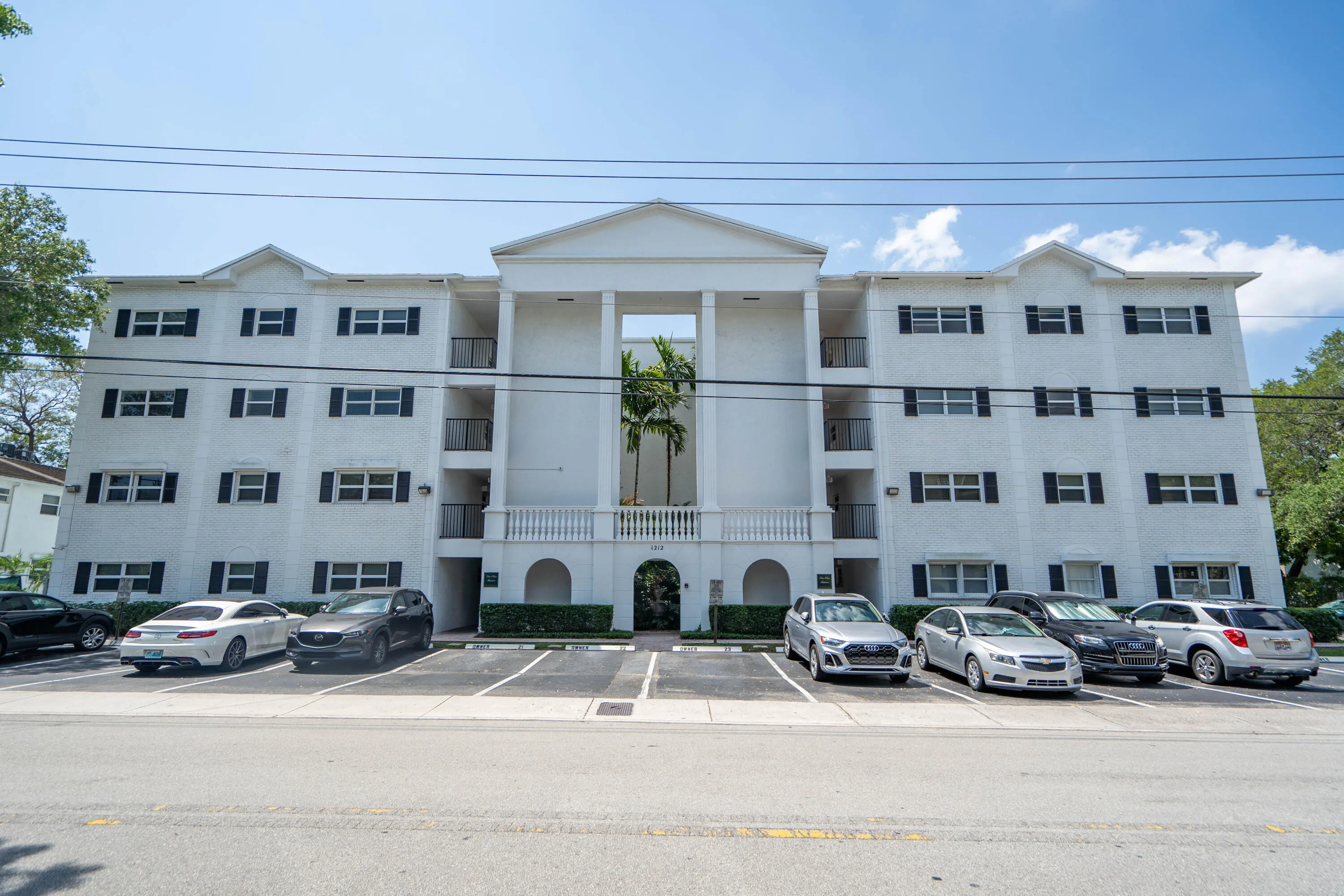 Three-story building with white exterior, black window shutters, and a central portico entrance
