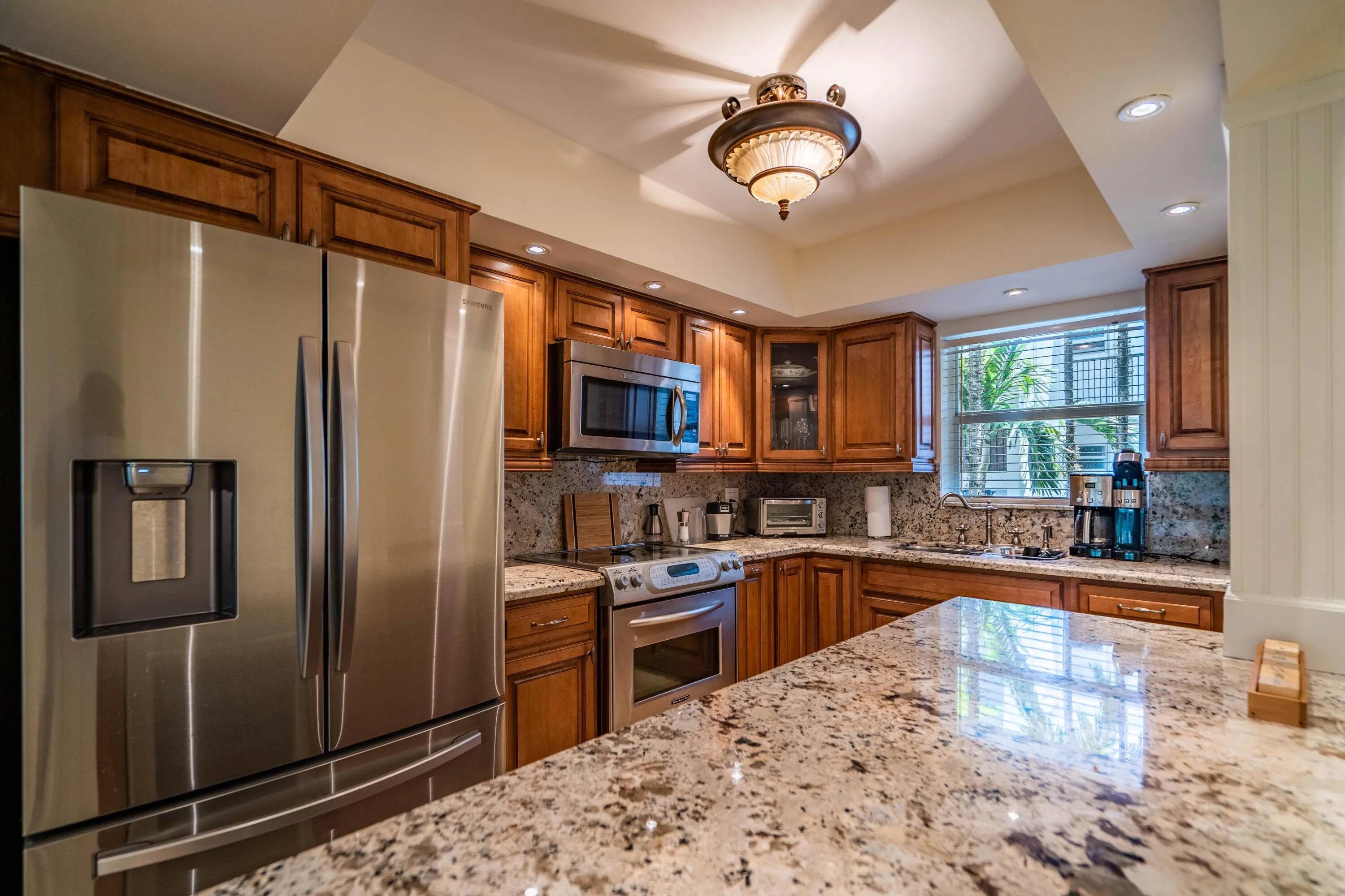 Kitchen featuring wood cabinetry, stainless steel appliances, recessed lighting, and stone countertops