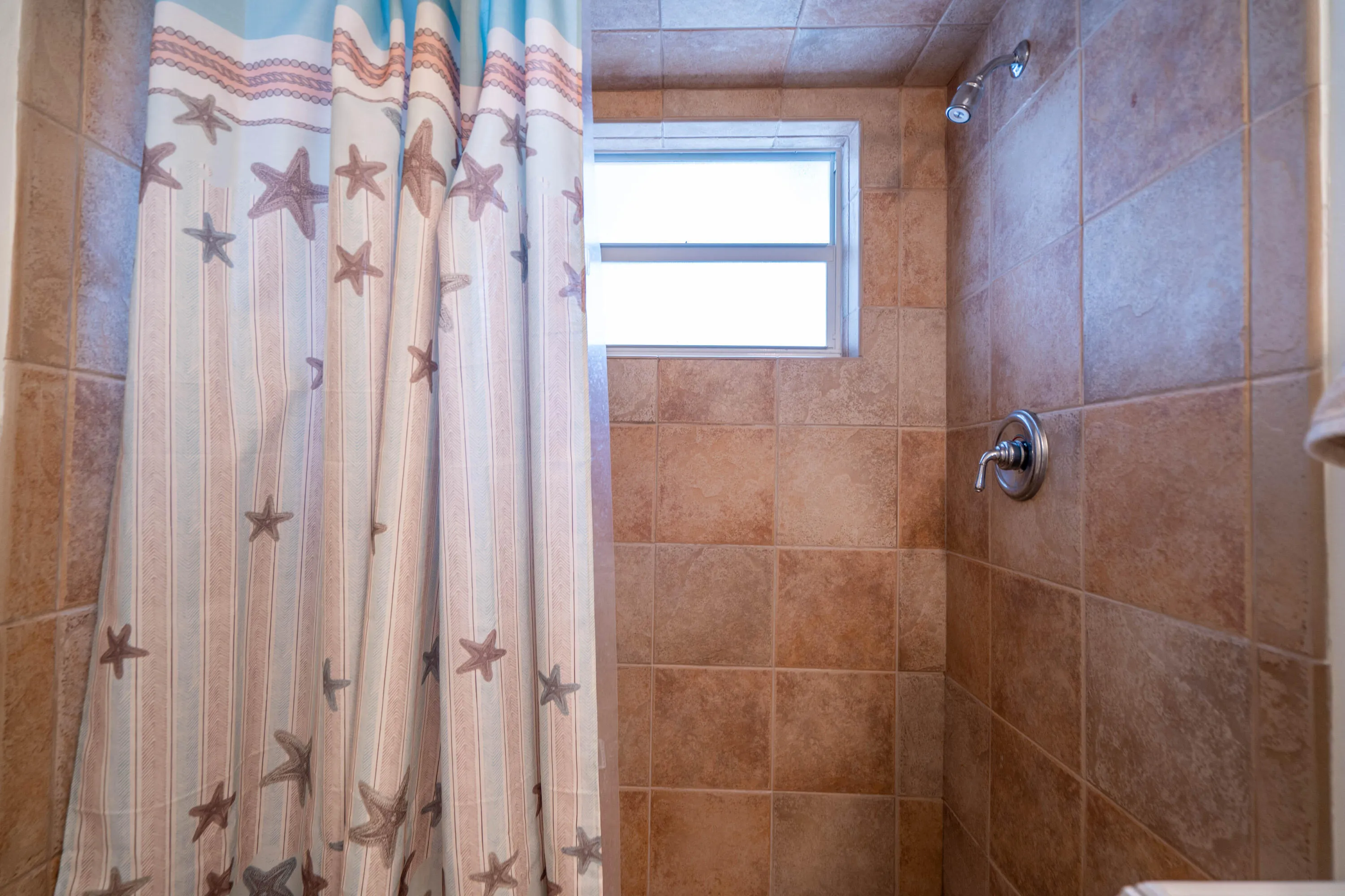 Tiled shower surround with a fixed window and a brushed nickel shower head and faucet