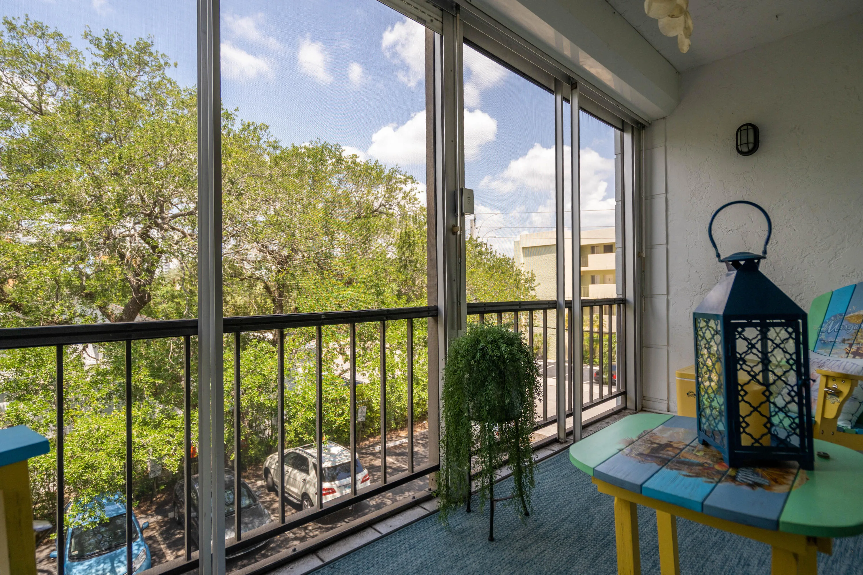 Enclosed balcony with sliding glass doors, textured wall finish, and a black metal railing