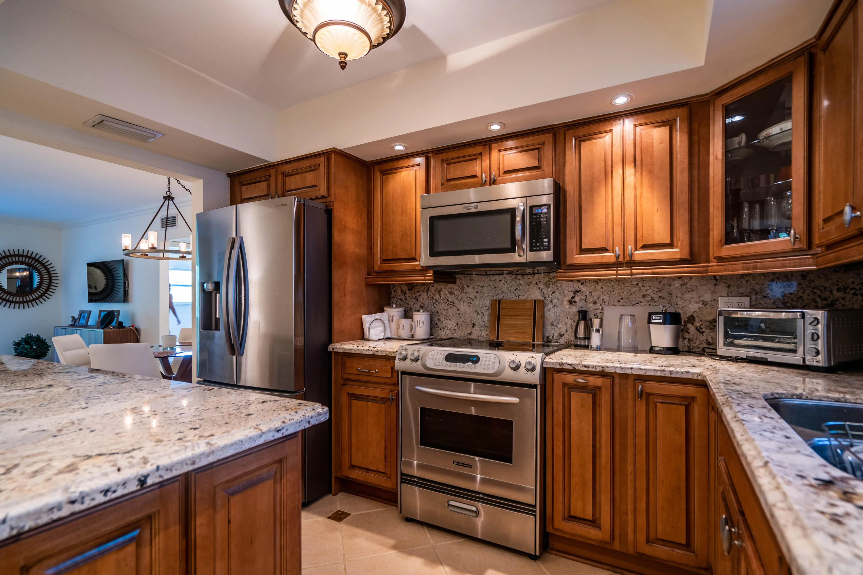 Stainless steel appliances, recessed lighting, wood cabinetry, stone countertops, and tile flooring