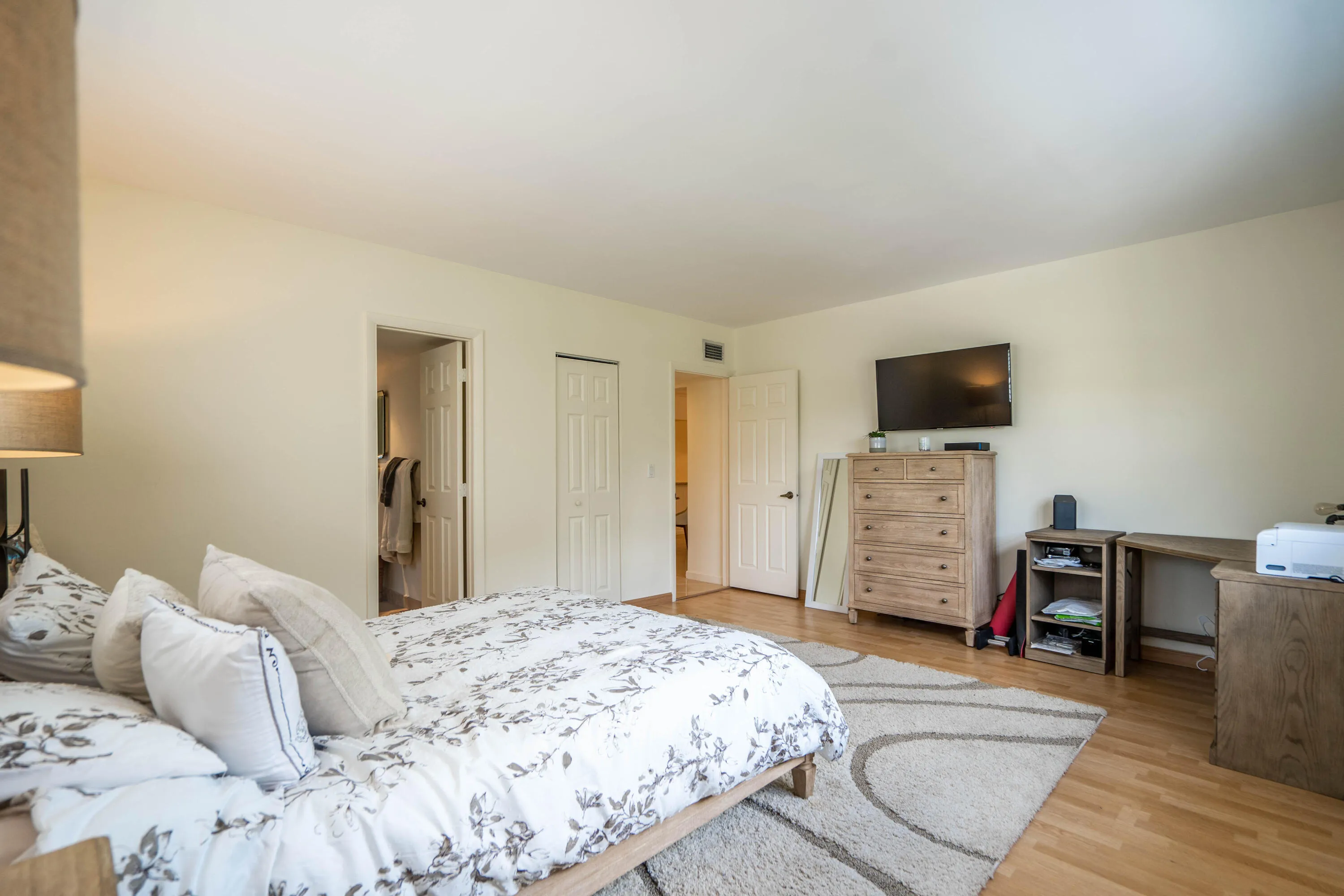 Spacious primary bedroom featuring hardwood flooring, multiple closet access points, and ample natural light