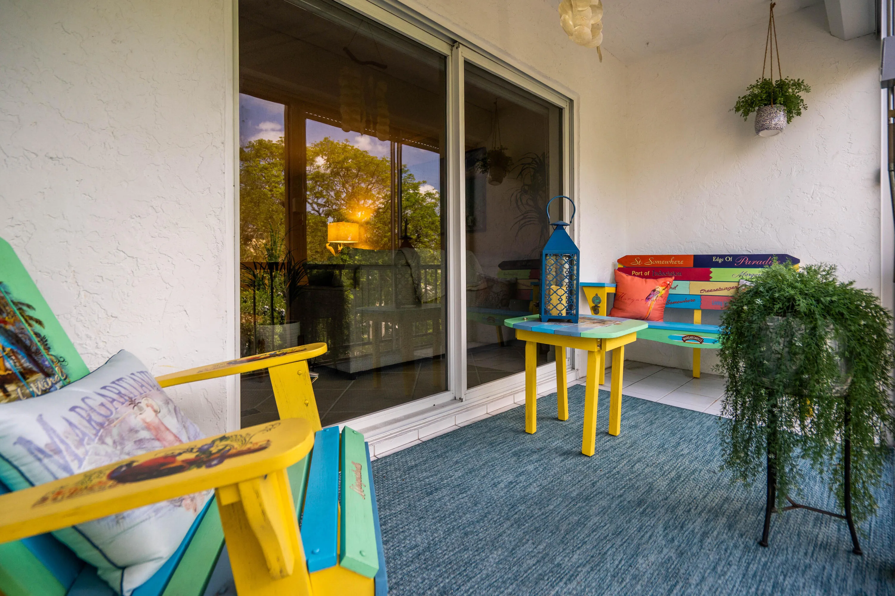 Covered patio with textured white walls, sliding glass doors, and a blue patterned outdoor rug
