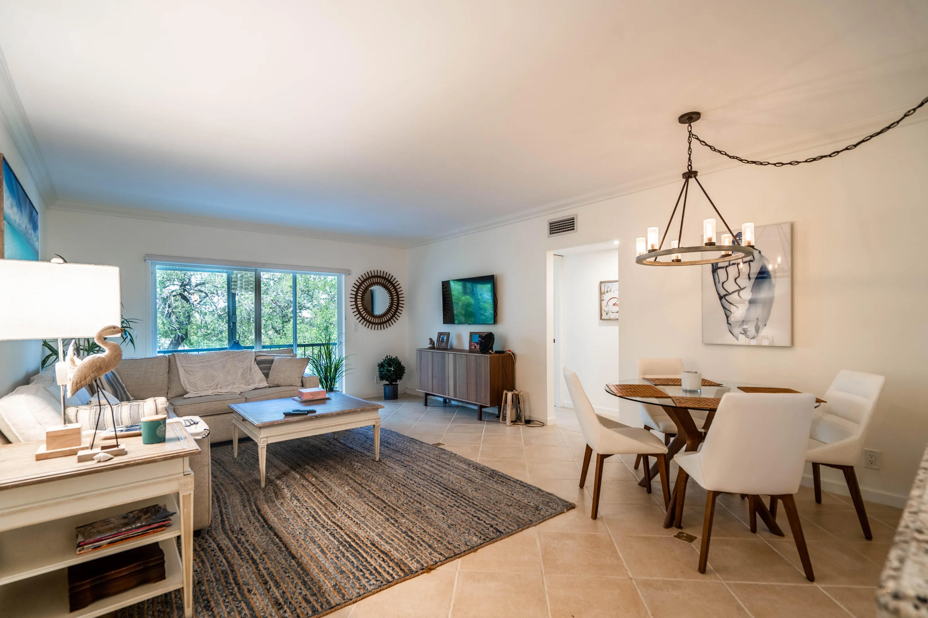 Spacious living area featuring large windows, crown molding, and tile flooring