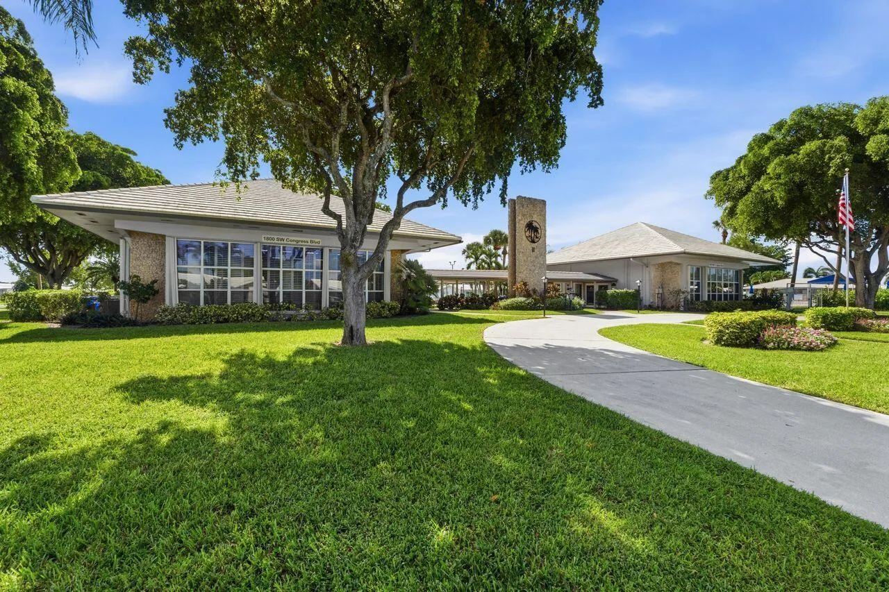 Expansive lawn with mature trees and a paved driveway leading to the Clubhouse with all the amenities