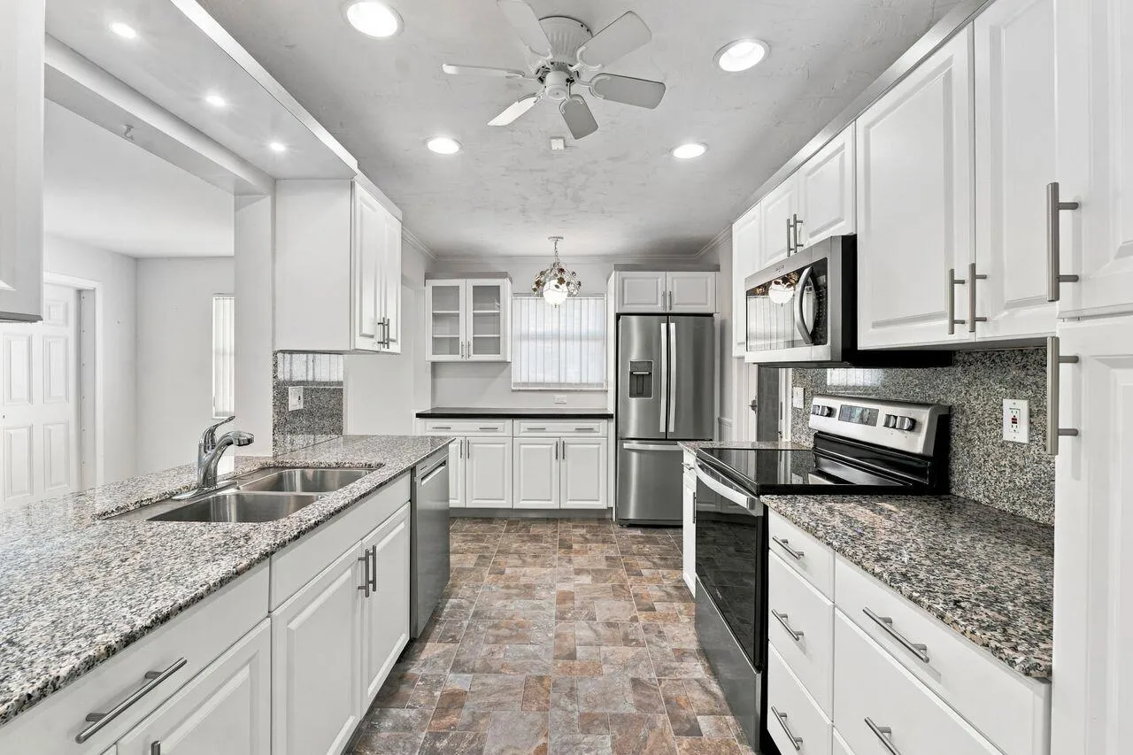 Kitchen featuring white cabinetry, granite countertops, stainless steel appliances, and recessed lighting