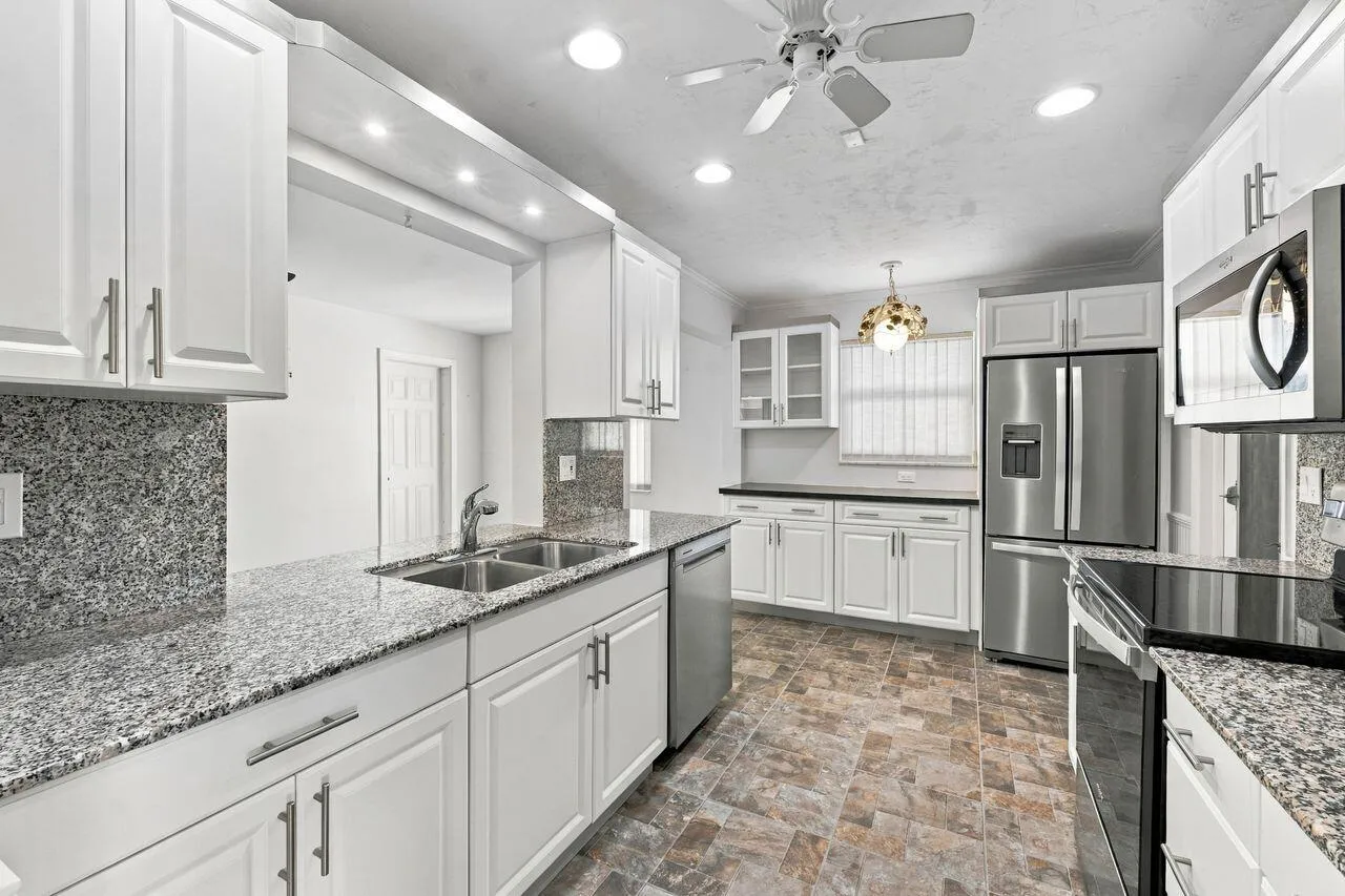 White shaker-style cabinetry with brushed nickel hardware, stainless steel appliances, granite countertops, and recessed lighting