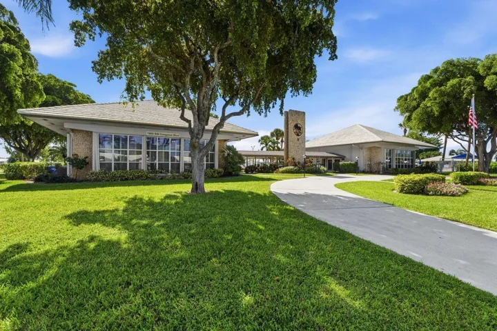 Expansive lawn with mature trees and a paved driveway leading to the Clubhouse with all the amenities