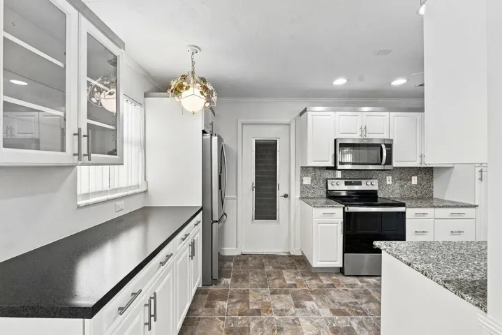 Kitchen featuring white cabinetry, stainless steel appliances, extra cabinetry with pantry and a tiled backsplash