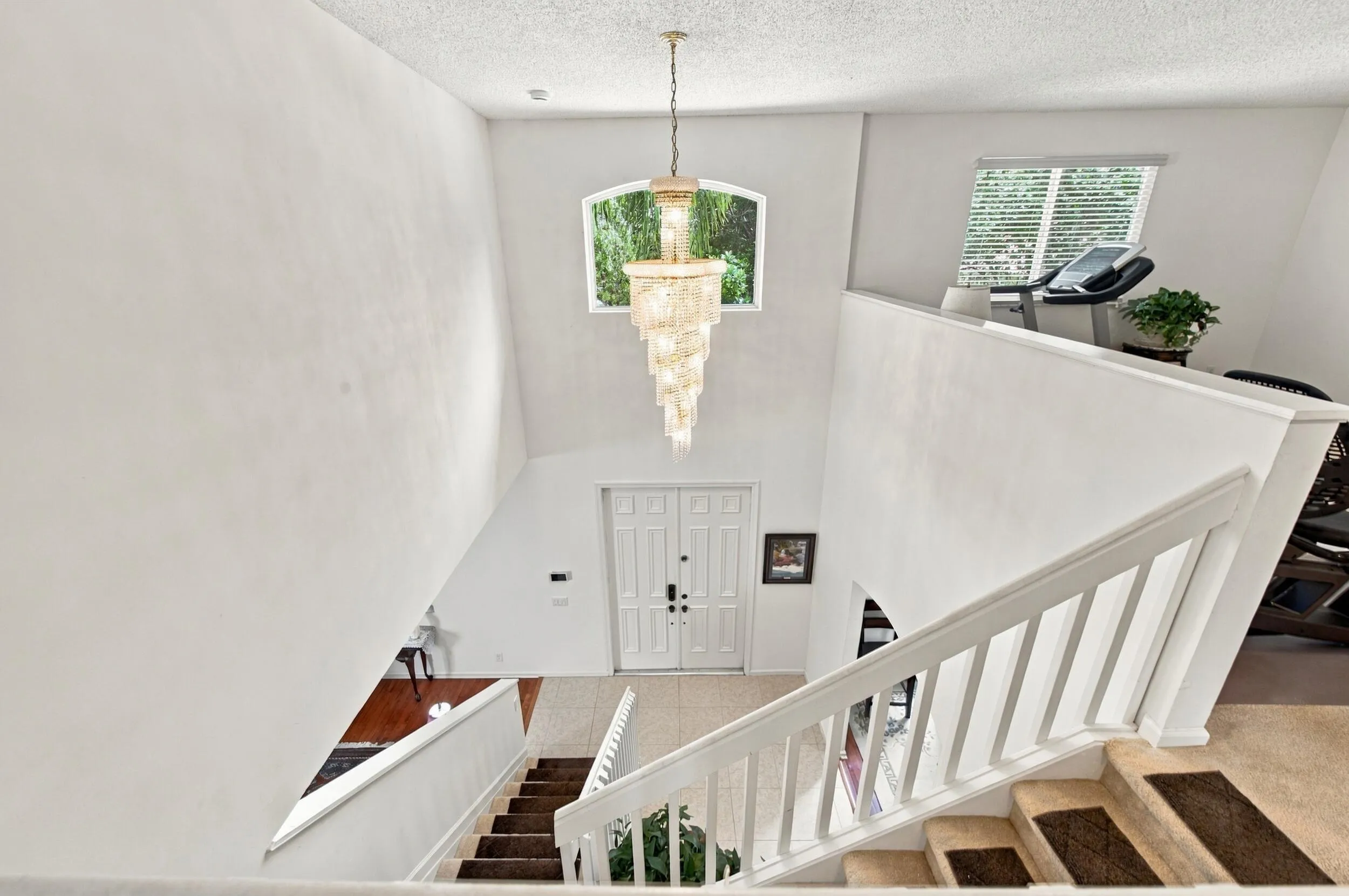 Vaulted ceiling entry with a decorative chandelier, arched window, and double entry doors
