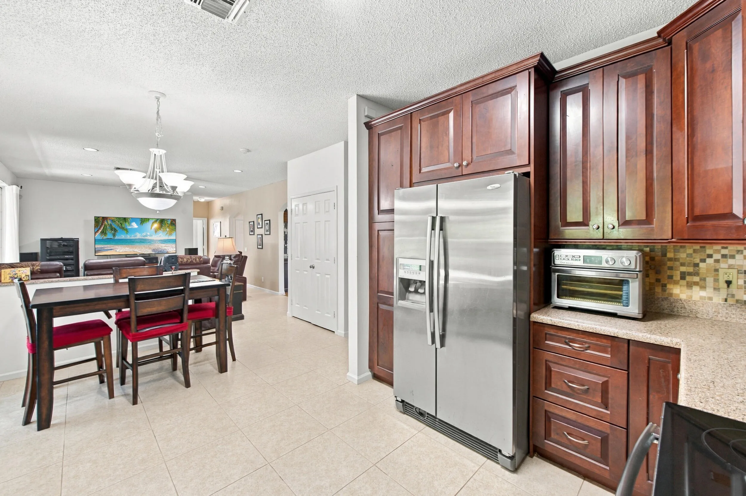 Kitchen featuring wood-finish cabinetry, stainless steel refrigerator, and mosaic tile backsplash