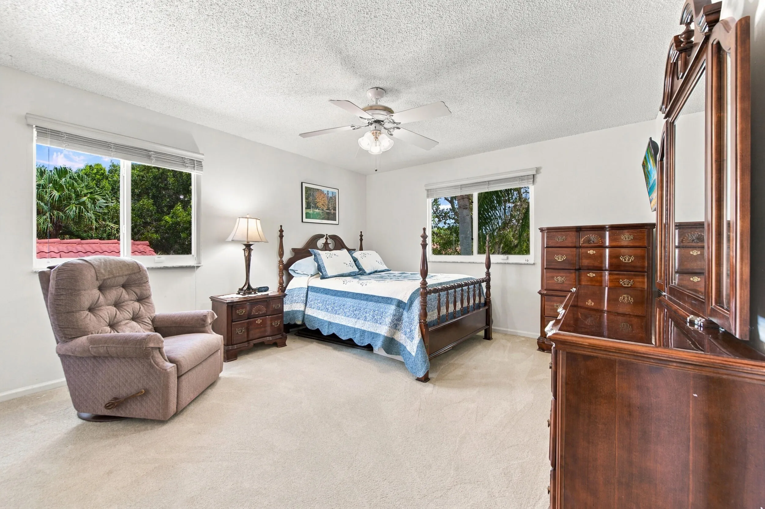 Textured ceiling, ceiling fan with integrated lighting, two windows with blinds, and light-colored carpeting