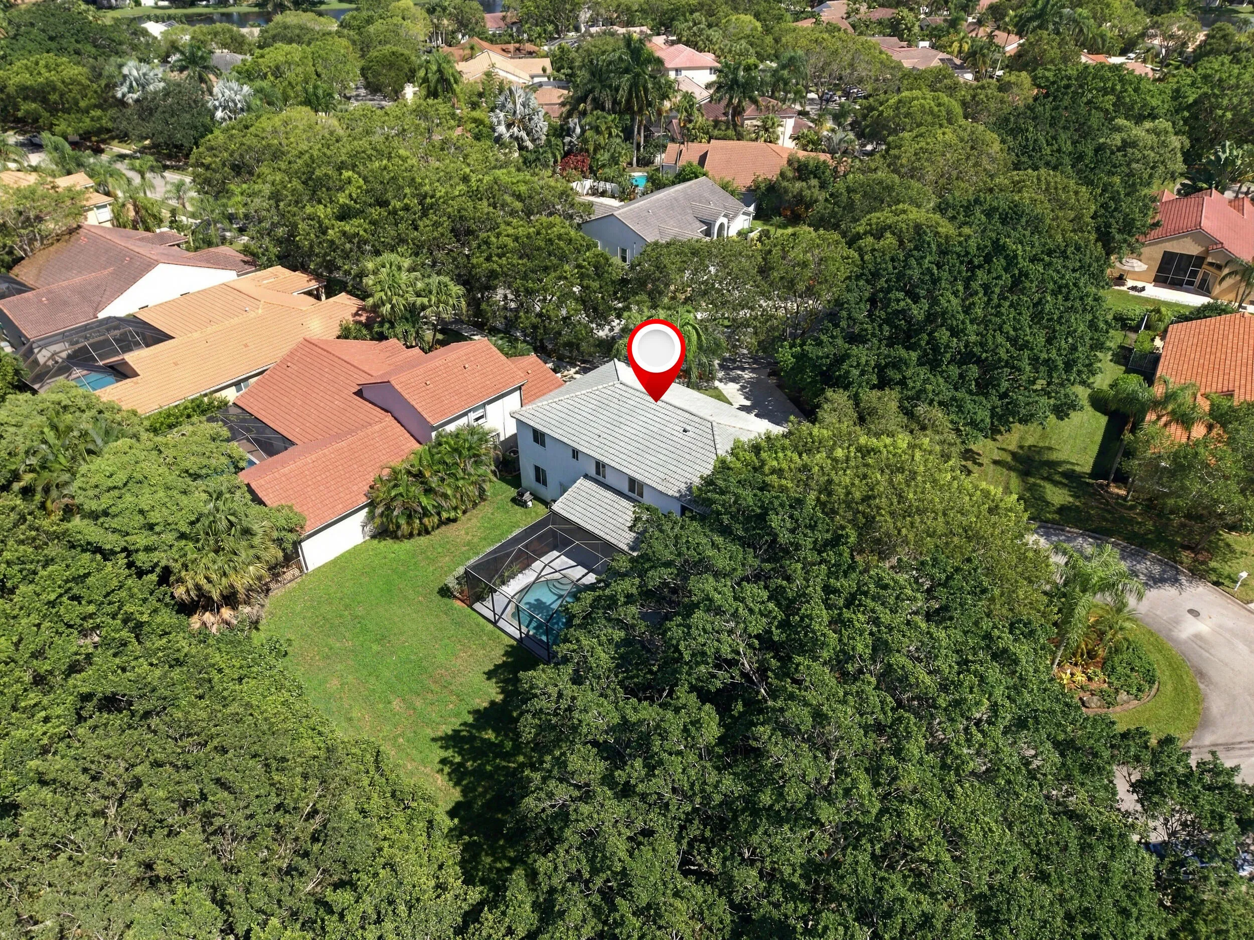 Two-story residence with a screened-in pool, surrounded by mature trees