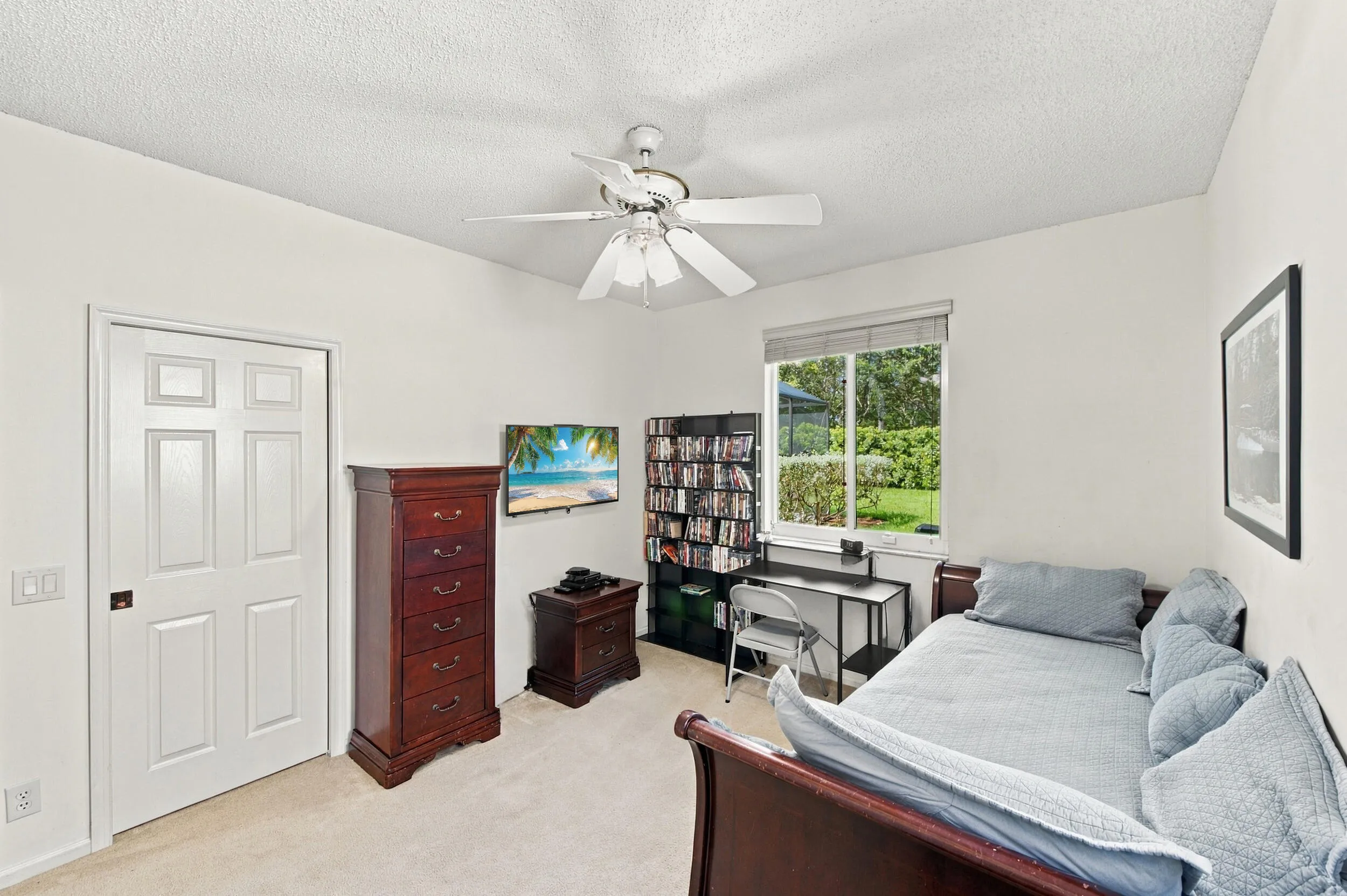Vaulted ceiling, ceiling fan, white six-panel door, window with outdoor scenery, and carpet flooring