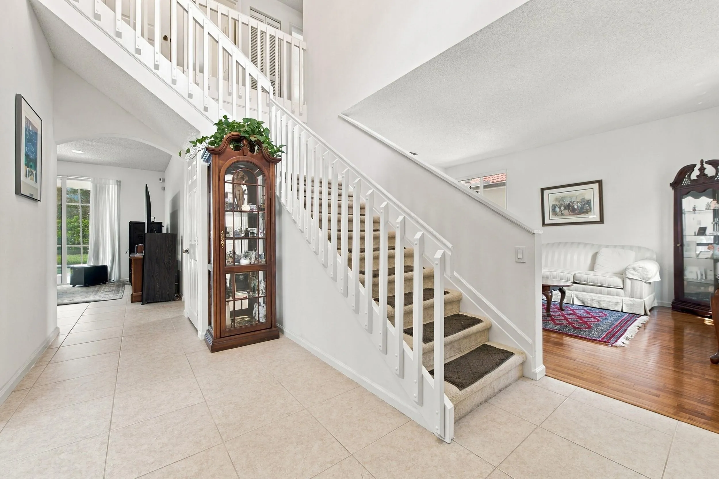 Two-story foyer with tile flooring, white staircase, and an upper-level landing with matching balusters