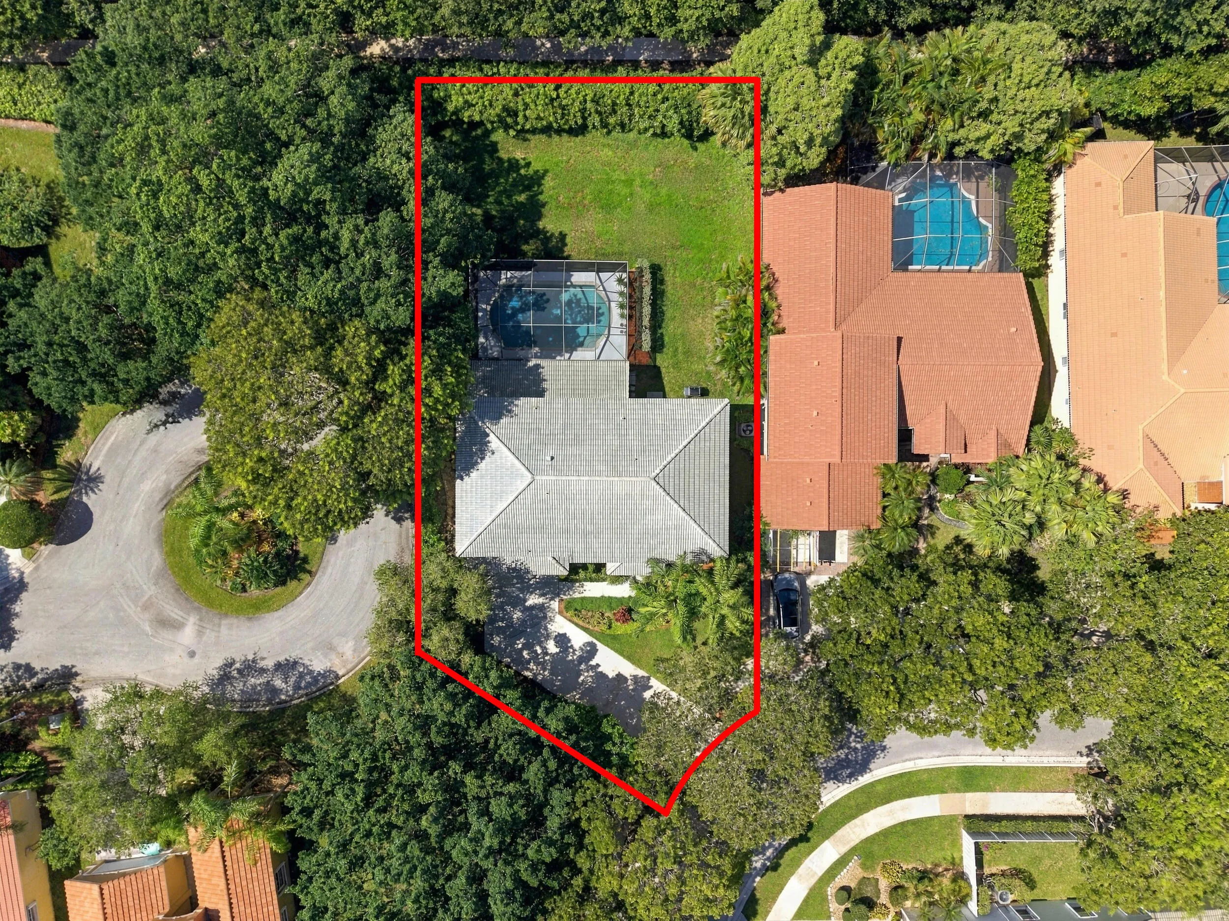 Residential property with a screened swimming pool, adjacent green space, and mature trees