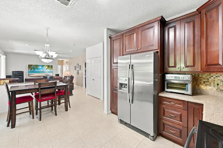 Kitchen featuring wood-finish cabinetry, stainless steel refrigerator, and mosaic tile backsplash