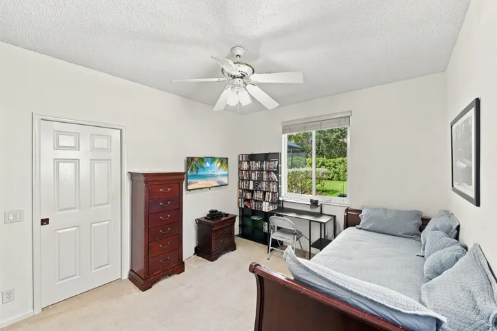Vaulted ceiling, ceiling fan, white six-panel door, window with outdoor scenery, and carpet flooring