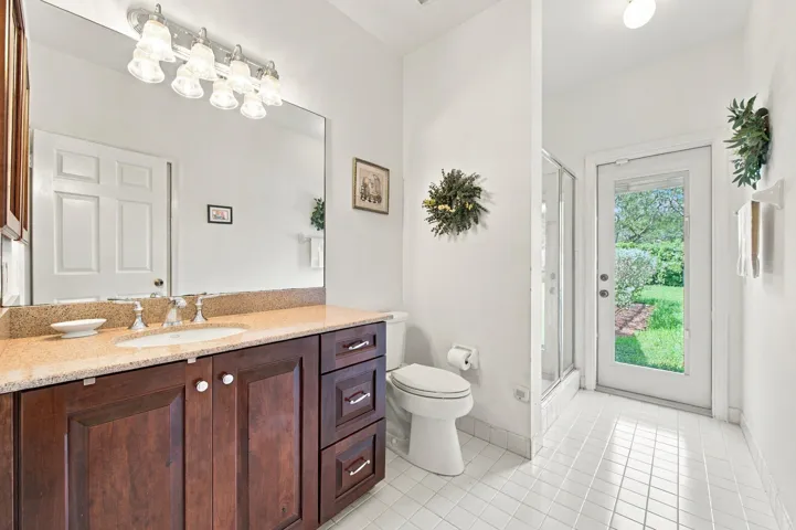 Vanity with wood-finish cabinetry, light-toned countertop, and integrated sink