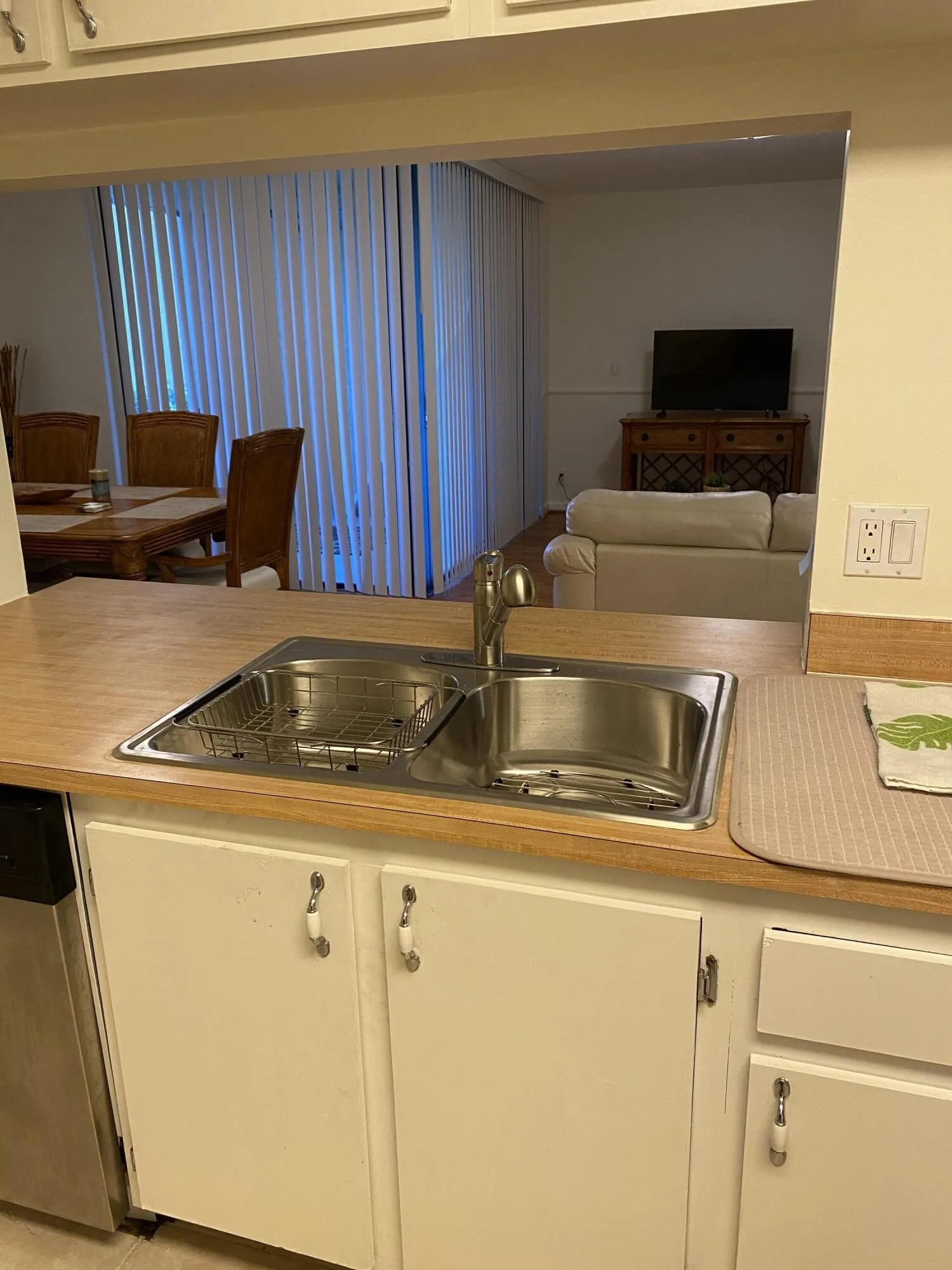 Kitchen featuring a stainless steel double-basin sink, laminate countertops, and white cabinetry