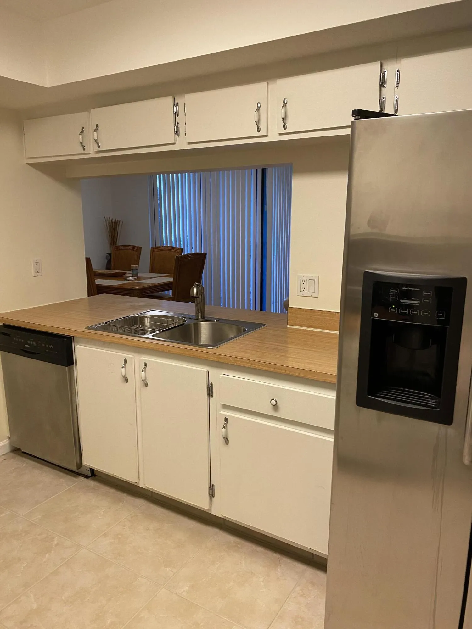 Kitchen featuring white cabinetry, wood-finish countertops, and a stainless steel refrigerator with an external dispenser